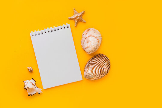 To do list or blank notebook with set of starfish, sea shell on yellow background. Travel, summer vacation or weekend, packing plan. lat lay, top view, copy space, place for text, minimal composition