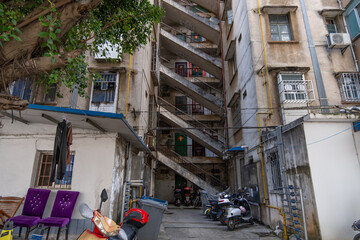 An old, weathered, and decaying walk-up residential apartment building with a winding staircase in...
