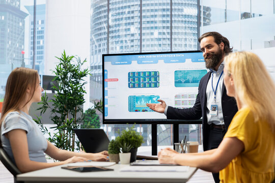Broker showing trading economic analytics figures on big screen in workspace to customers. Market index listings values going up and down on large monitor, price volatility concept