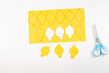 yellow paper cutouts in the shape of flames, step in creative process, process of creating multiple...