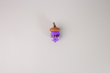 a painted purple acorn on grey background, step in creative process, DIY,