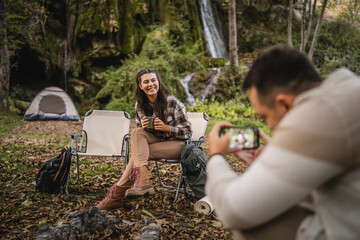 boyfriend take a photo with mobile phone of girlfriend in front tent