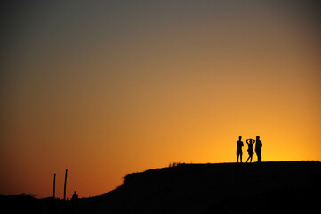 Fototapeta premium Friends silhouetted by a stunning hilltop sunset, creating lasting memories