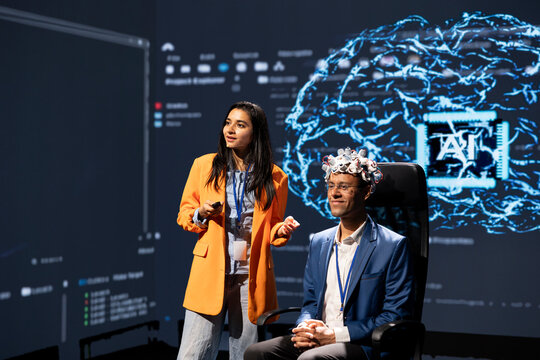 Specialists speaking at neuroscience tech expo, exploring latest AI technology and neural implants. Smiling researcher and guest presenting latest EEH headset and artificial intelligence innovations