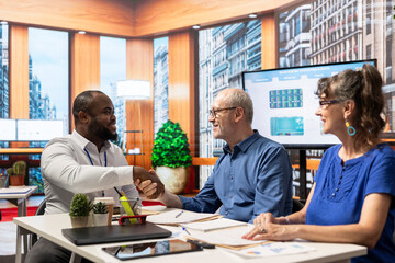 Financial adviser shaking hands in agreement with elderly man, ensuring a partnership to help them secure their pension and retirement planning. Meeting in modern office for counseling.