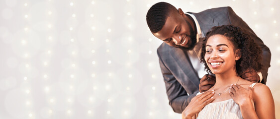 Obraz premium Black guy in love giving his happy girlfriend golden necklace, festive interior, copy space