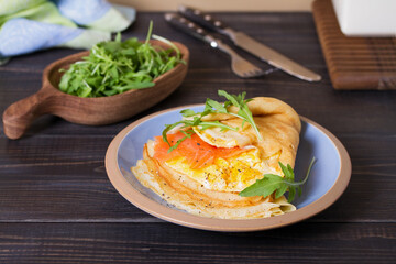 Pancake wrapped with  scrambled egg and salmon. Crepe.