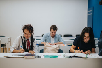 A group of students concentrated on their tasks in a classroom. The image captures an atmosphere of learning and collaboration, with a professor possibly assisting in the background.
