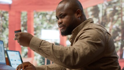 Entrepreneur using a card to make an online shopping payment via electronic banking, purchasing things to help the startup activity. Business owner makes a payment at his home office. Camera A.