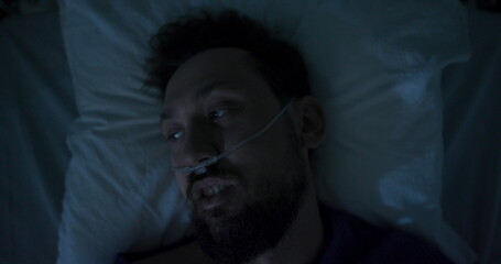 Patient lays in bed, looking directly into the camera.