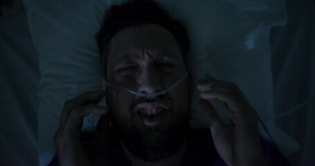 Fototapeta premium Young person regaining consciousness in hospital room suffering from migraine headache.