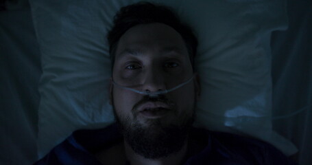 Patient waking up in hospital bed with breathing tube.