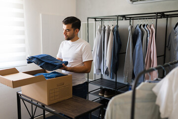 Handsome Latin man organizes his walk-in closet while unpacking a box of clothes