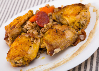 Appetizing fried chicken thighs with pearl barley and braised vegetables on white plate..