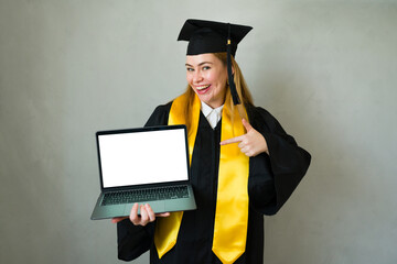 Online graduate student smiling and pointing at laptop screen against a gray studio backdrop