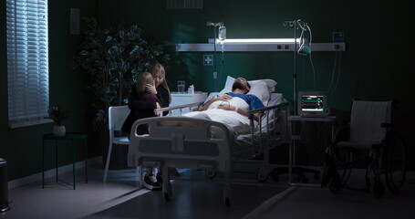 In hospital, mom and child sit near unconscious dad.