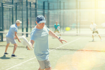 Four men practice playing padel on an outdoor tennis court