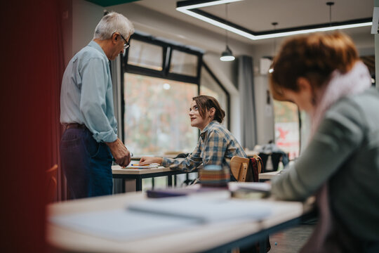 An elderly professor interacts with attentive students in a contemporary classroom. The environment fosters learning and communication, highlighting the educational bond between teacher and students.