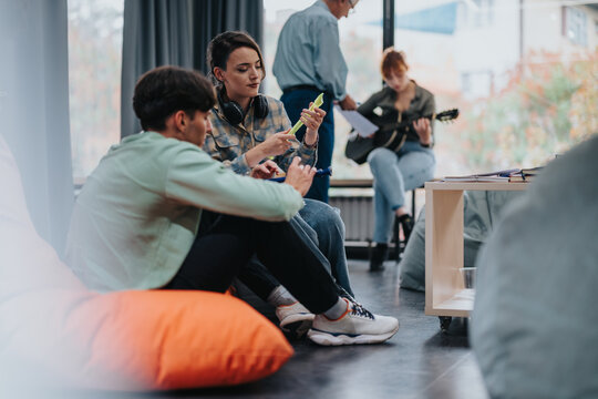 A group of college students participate in a music class, discussing and collaborating in a relaxed, creative environment. Instruments and study materials are visible.