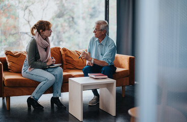 A senior professor offers guidance to a young female student in a relaxed and comfortable environment, fostering learning and academic development.