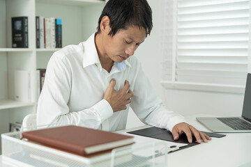hand hold chest with heart attack symptoms, asian man working hard have chest pain caused by heart disease, leak, dilatation, enlarged coronary heart, press on the chest with a painful expression