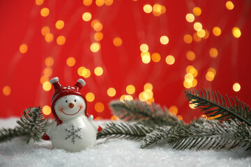 Cute decorative snowman and fir branch on artificial snow, space for text