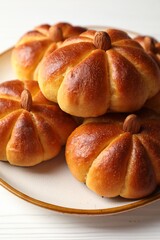 Tasty pumpkin shaped buns on white wooden table, closeup