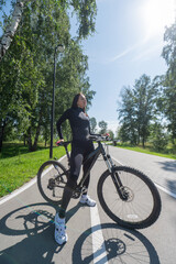 Fototapeta premium Caucasian woman riding a bike in a park. Vertical photo. 