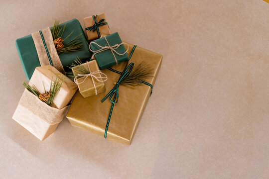 Beautifully wrapped Christmas gifts with pine and ribbon accents on table, at home, copy space