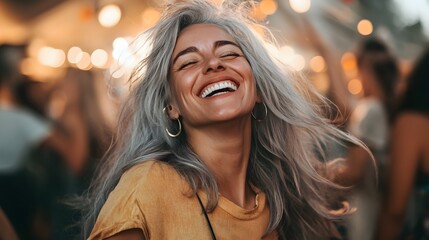 gray haired woman smiling, feeling carefree, relaxed and happy, dancing and listening to music, having fun at a party. 