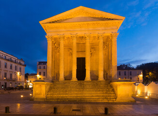Fototapeta premium Night view of lighted Maison Carree of Nimes at dusk, France