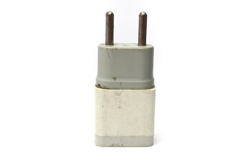 A close-up of a white, slightly dirty electrical wall charger with two metal prongs. The charger is isolated against a white background.