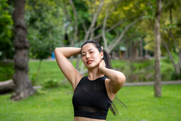 A woman in a black tank top is posing in a park