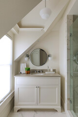 A modern bathroom with chrome fixtures and a marble vanity. Pictured in a traditional cottage with natural light coming in through a bathroom window. Located in Carlton, Oregon.