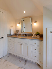 A modern bathroom with white vanity, countertop, mirror, and light fixtures. Pictured in a traditional cottage in Carlton, Oregon.