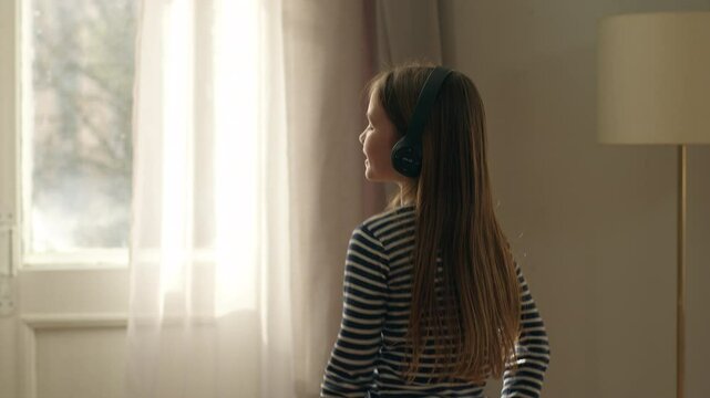 Caucasian European little girl dancing child daughter dancer headphones listen music sing songs tech fun childhood home weekend enjoyment energetic movement celebration pleasure vacations kid device