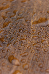 Close up of a stained and sealed waterproof wooden board covered in water drops