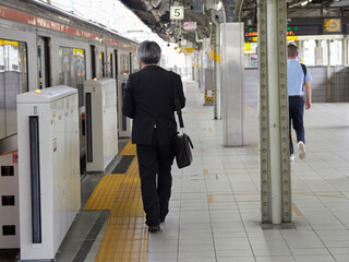 名古屋駅のホームで電車に乗る中年サラリーマンの姿
