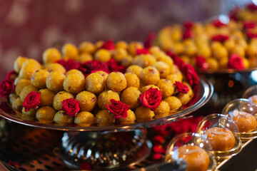 Round-shaped Balushahi stacked on a plate, decorated with a few roses.