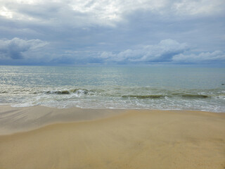 Sea view with the beach, waves, blue sky, and fluffy clouds.
