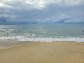 Sea view with the beach, waves, blue sky, and fluffy clouds.