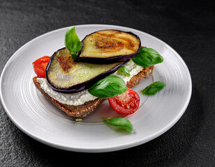 Sandwiches with cream cheese, fried eggplant, basil, tomato and microgreens on white plate, close up.