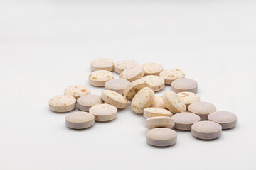 An image of several large round pharmaceutical pills piled on a white background.