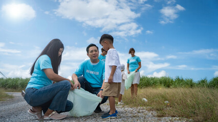 Obraz premium A family of four is picking up trash in a field. Scene is positive and encouraging, as the family is working together to make a difference in the environment