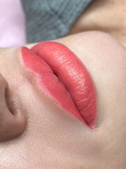 Fototapeta premium permanent makeup on the lips of a young woman of a delicate peach shade close-up, a girl after a cosmetic procedure with smooth and clean healthy skin. 