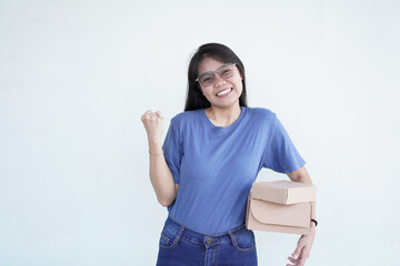 Beautiful Asian woman smiles joyfully, giving a 'yes' gesture while holding a package box against a...