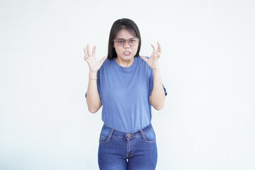 Beautiful Asian woman shows an angry gesture, her brows furrowed and fists clenched, expressing...