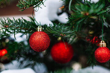 Red Christmas balls and garlands on branch. Christmas tree with decor. Holiday season, street decorations.