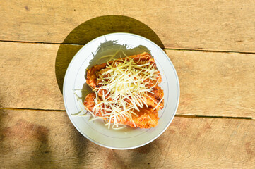 Fried Banana Cheese serve with cheddar cheese graters on white plate on the wooden table.