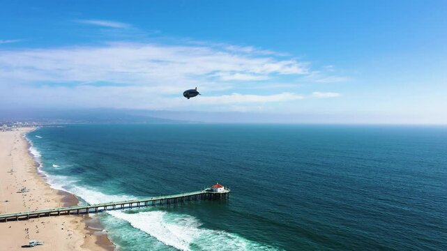 Goodyear Blimp Flying Over The Manhattan Beach Pier In California, United States. Aerial Wide Shot